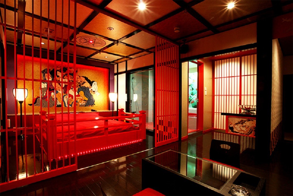 Красивая японка в необычных очках устроила красивый стриптиз на полу комнаты с красными стенами 